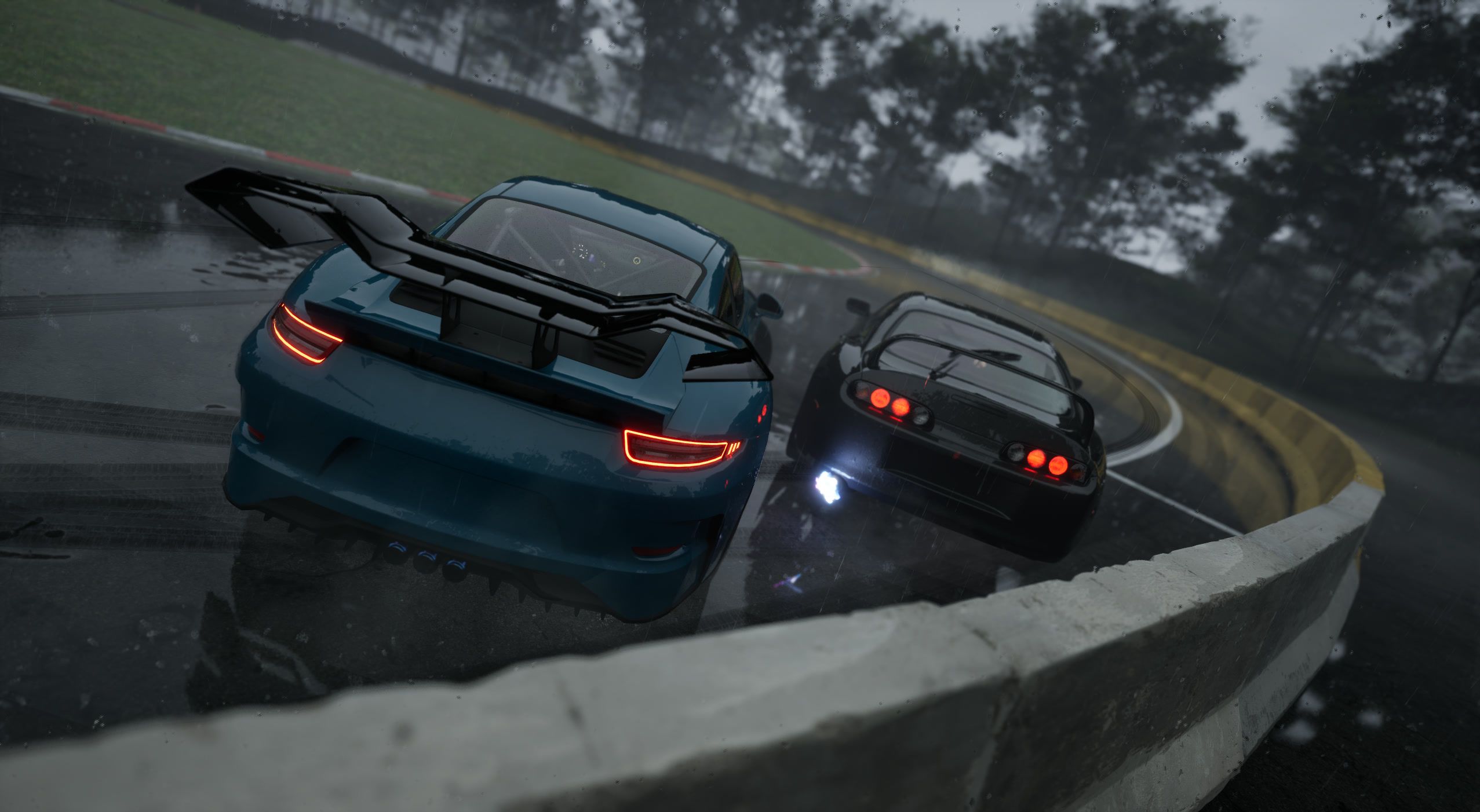 Rear view of the teal leader and black chaser along a wet concrete wall, tail lights glowing